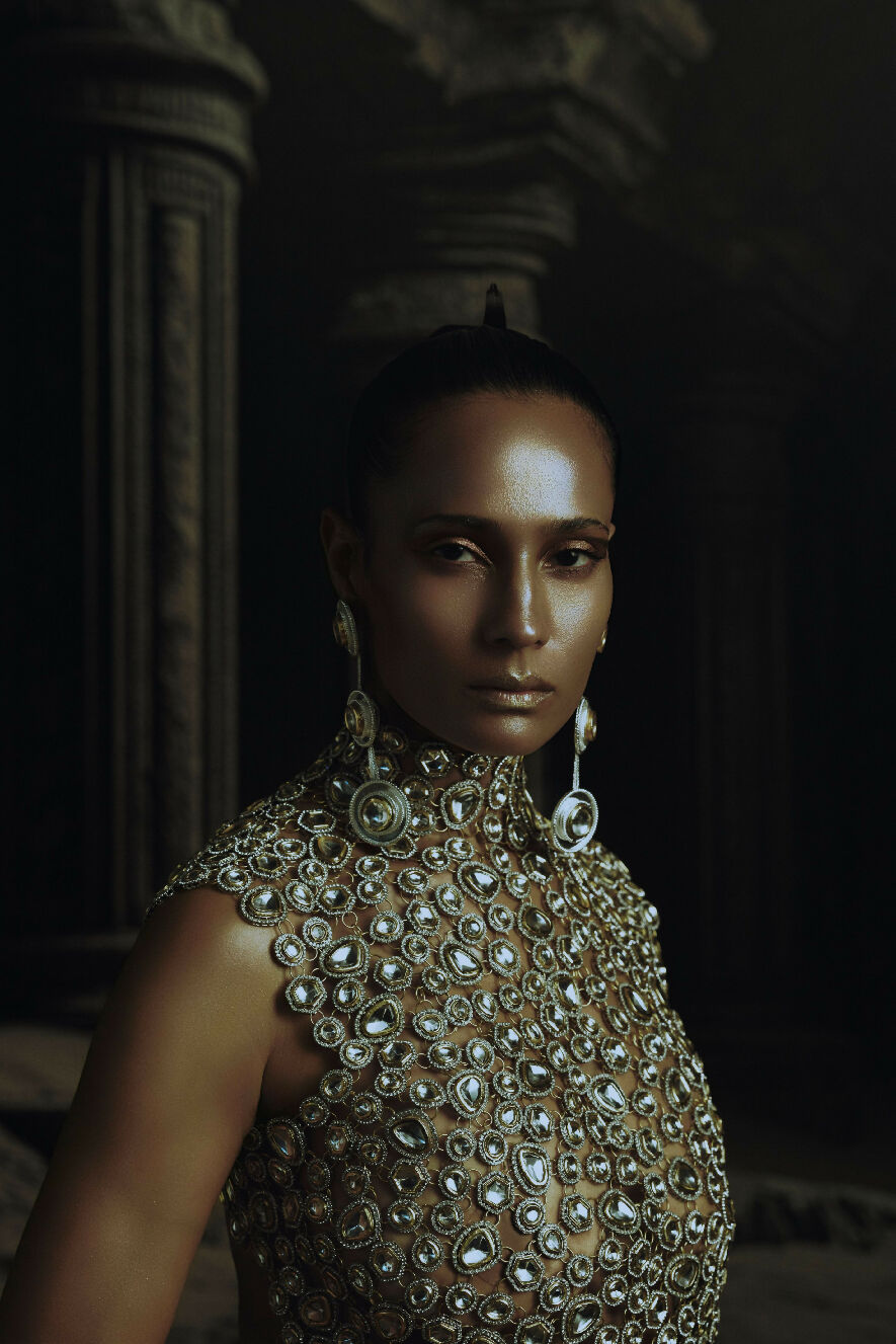 Woman wearing a heavily embellished top in a dark setting
