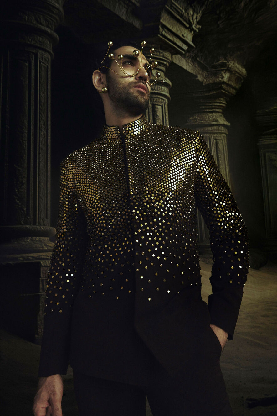 Person wearing a sparkling black outfit in a dark, possibly ancient setting