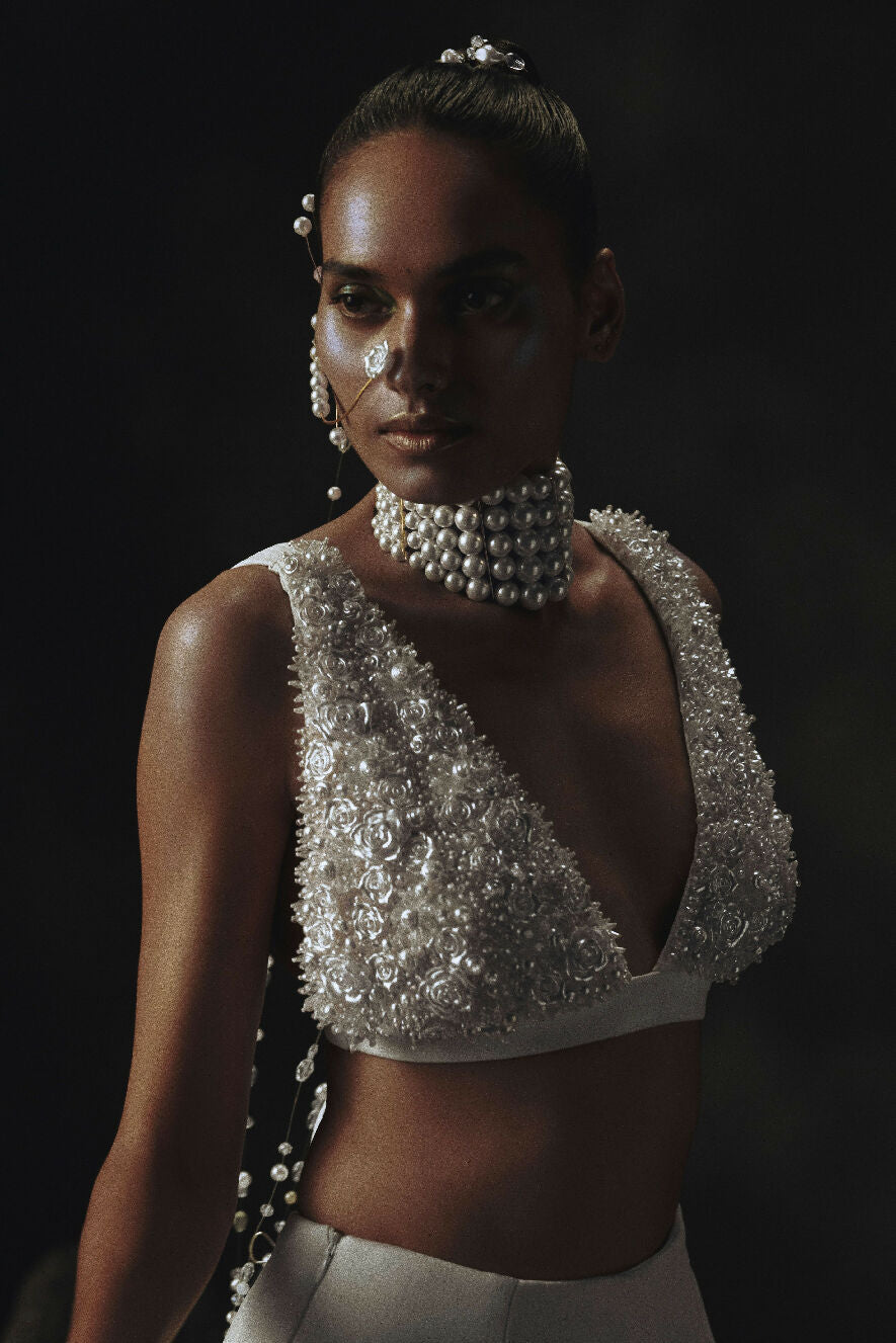 Model wearing a sparkling silver top with a dark background