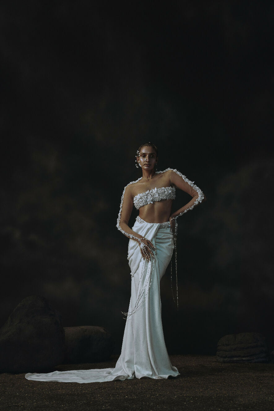 Model wearing a white beaded dress against a dark background