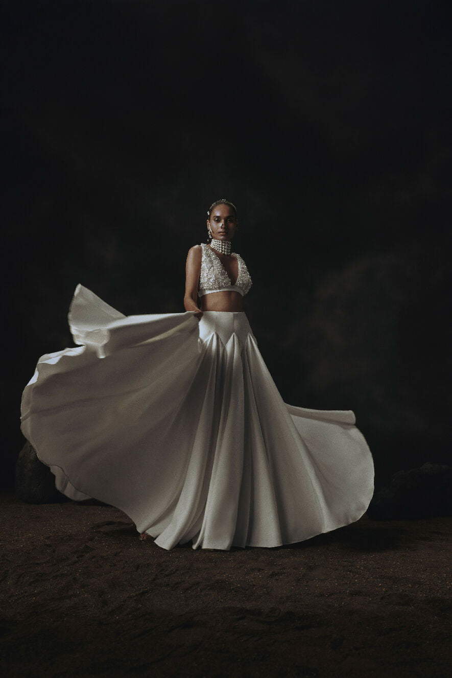 Woman in a flowing white Lehenga against a dark background