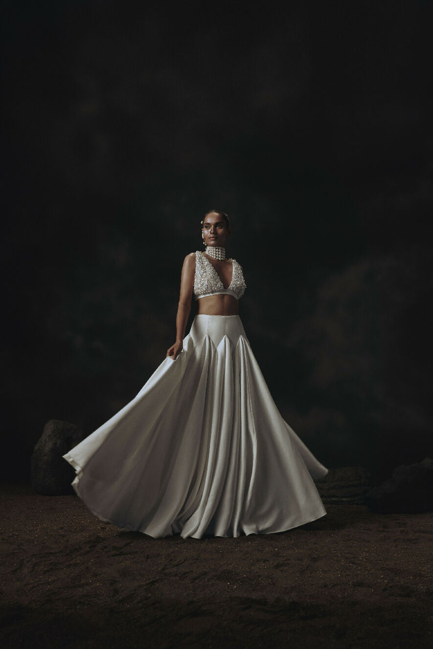 Woman in a white Lehenga standing against a dark background