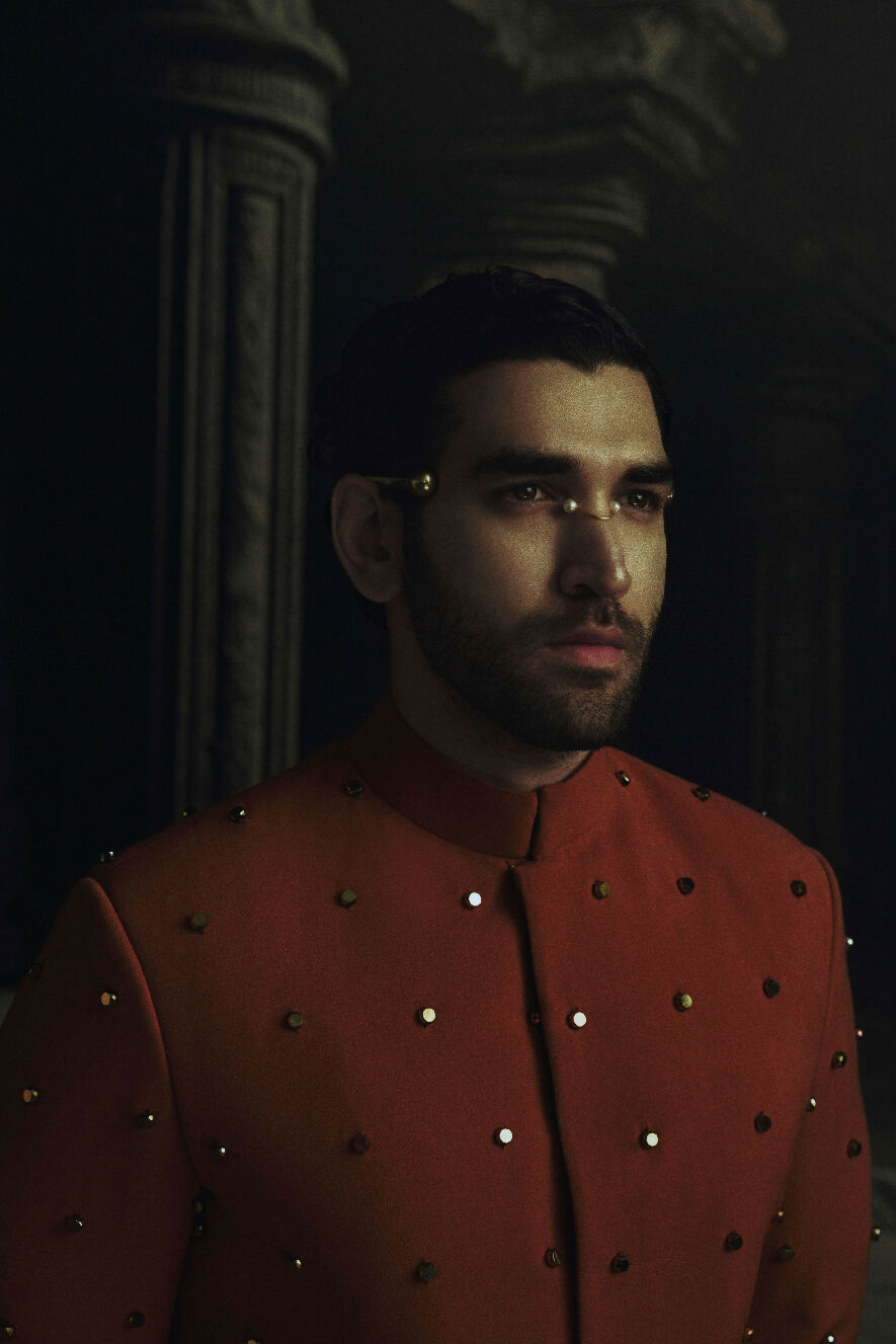 Man wearing a red jacket with gold buttons in a dark setting