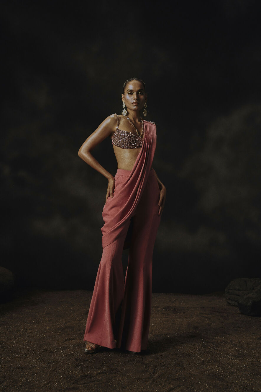 Woman in a pink saree against a dark background