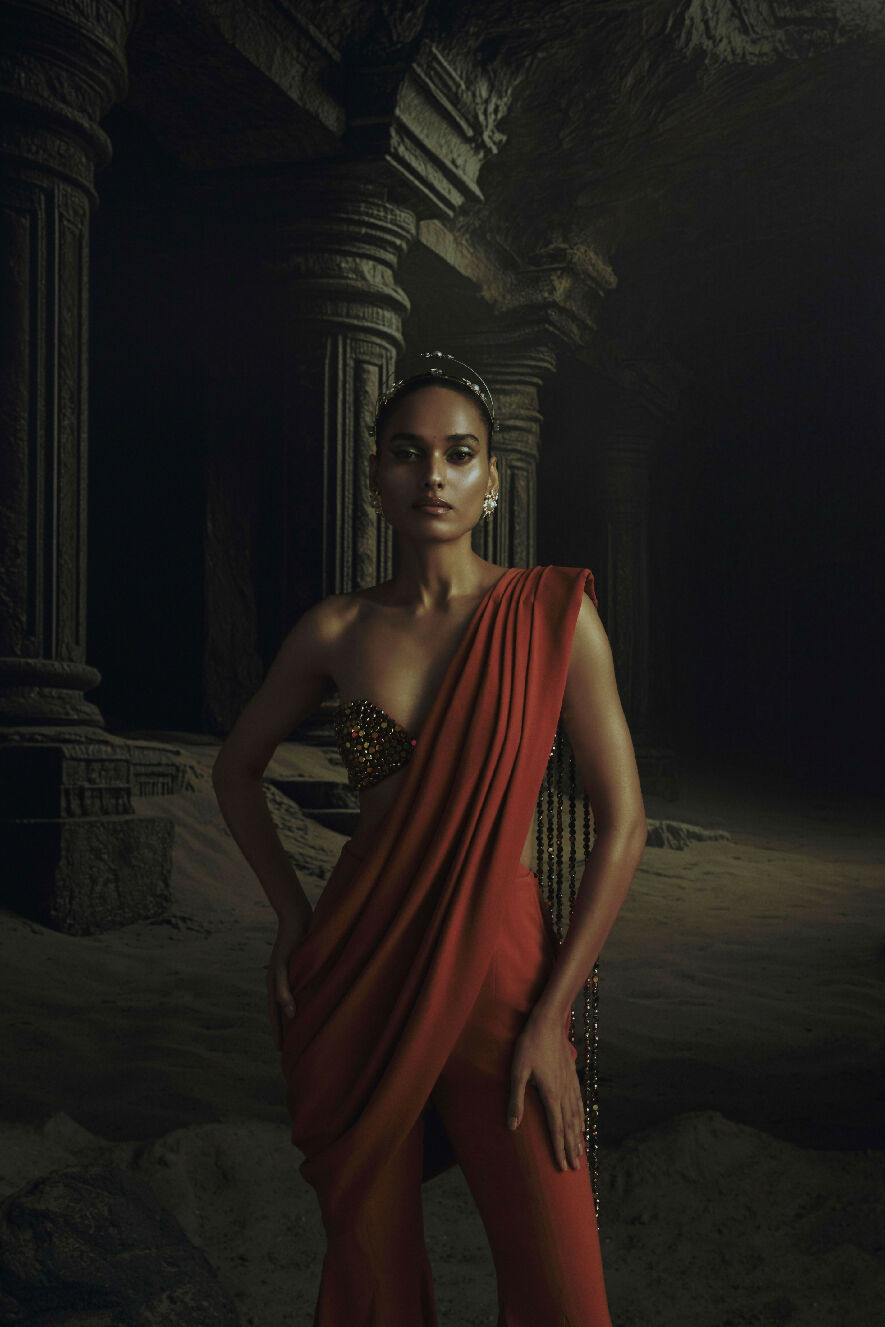 Woman in a red outfit standing in a dark, ancient temple-like setting