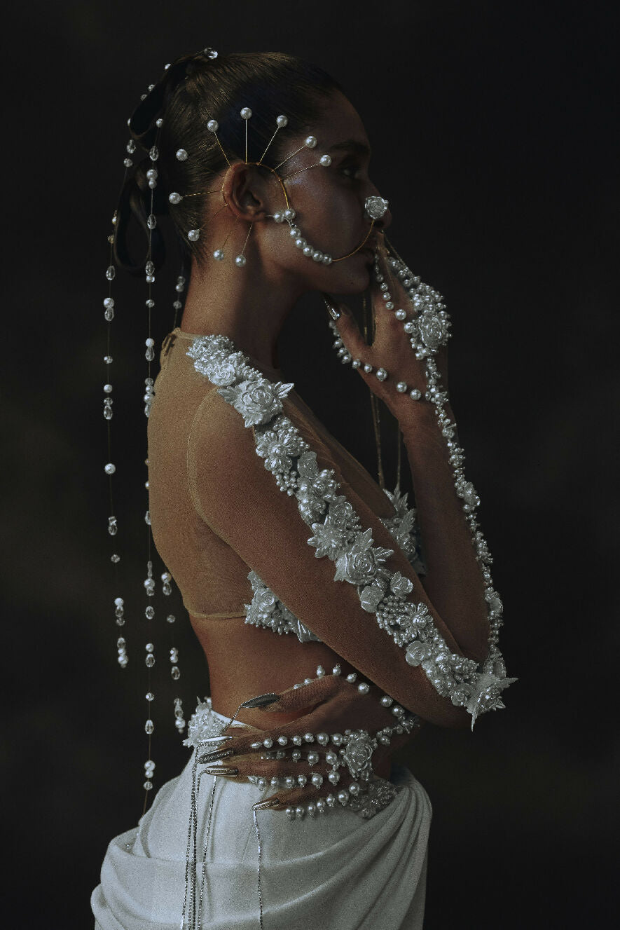 Woman in elaborate silver jewelry and dress against a dark background