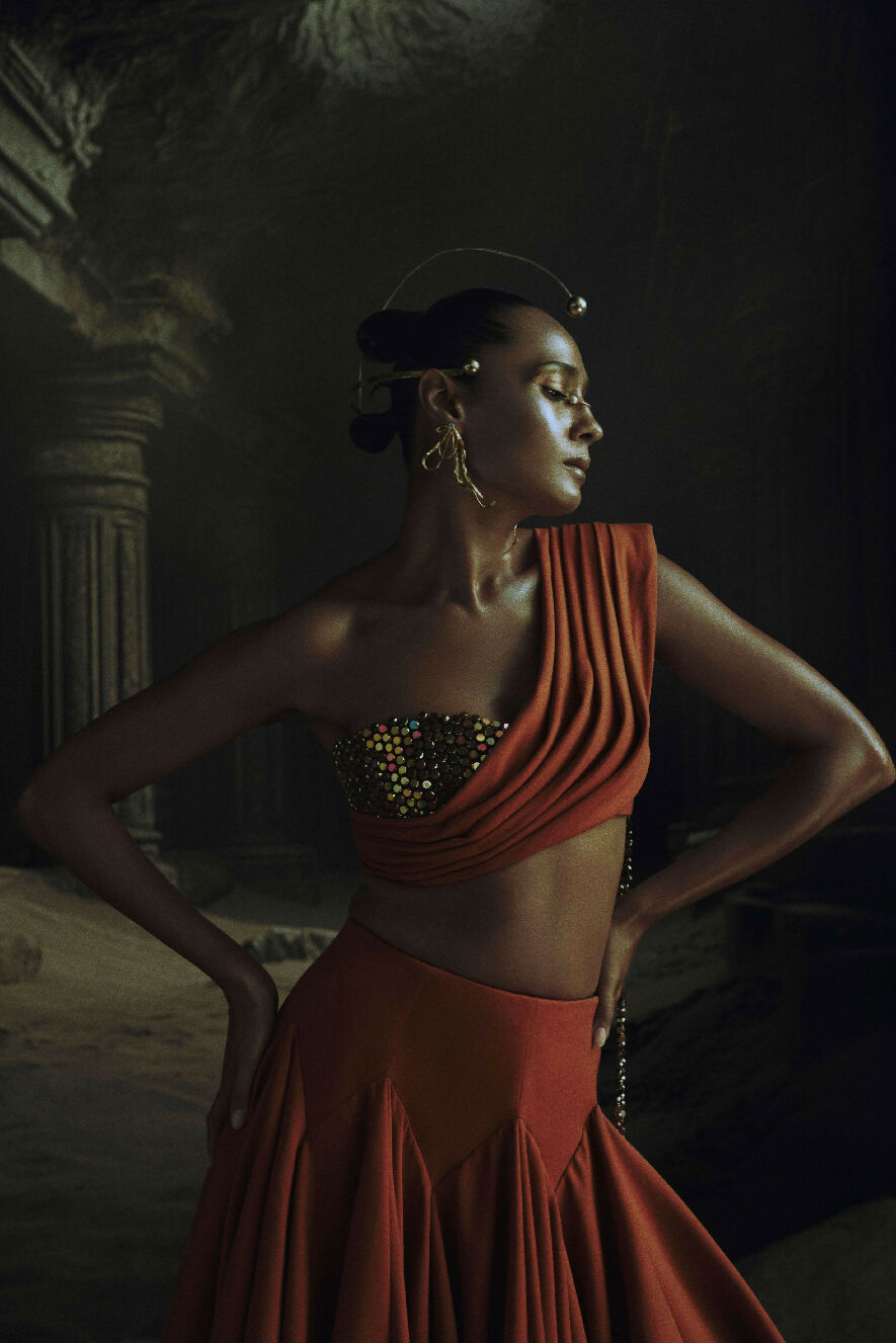 Woman in a red outfit with a dark, classical architecture background