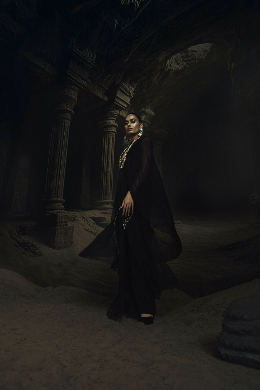Woman in a Kundan dress standing in a dark, ancient temple-like setting